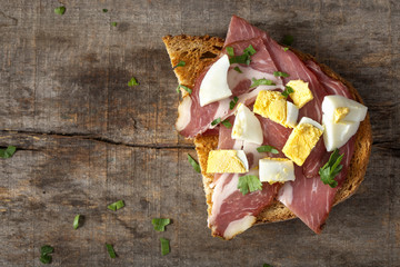 Open sandwich with pork meat, pieces of boiled eggs and chopped parsley
