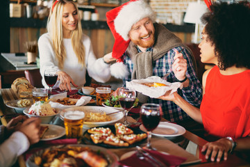 Friends having dinner at home at Christmas eve. Winter holidays concept.