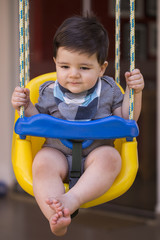 Beautiful brazilian baby boy looking at camera. baby on the swing. Happy baby.