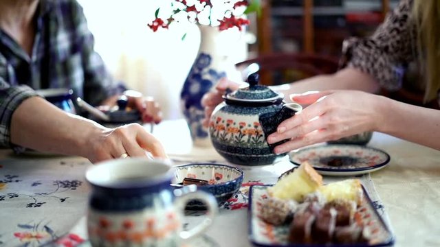 People around a table drinking tea focus on hands, 240fps
