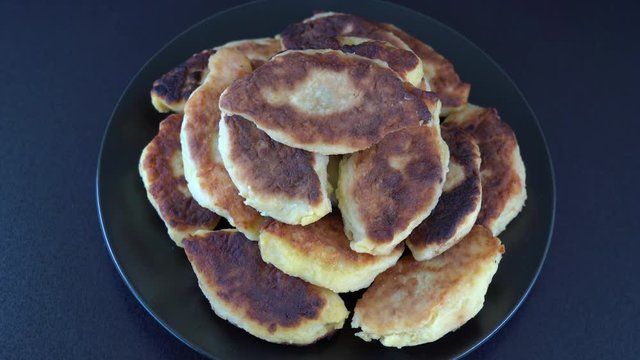 Potato cakes, ukrainian name potato zrazy, stuffed mushrooms or meat or cheese with herbs cream are fried in vegetable oil on black background, close up, rotates. Traditional Ukrainian cuisine