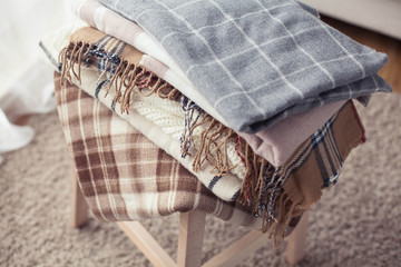 Blankets close up. Autumn cozy interior. A stack of warm blankets lie on a wooden chair. Autumn. Winter.