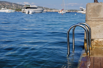 chromed iron  railing for the descent  for swimming in the sea on the background of blue sea