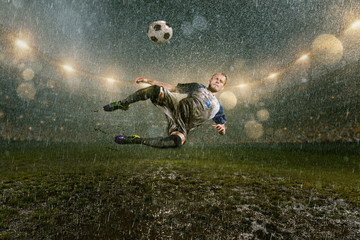 Obraz na płótnie Canvas Soccer player on professional soccer night rain stadium. Dirty player in rain drops kicks the football ball in flight