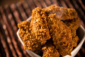 Bucket full of crispy kentucky fried chicken with smoke on brown background. Selective focus.