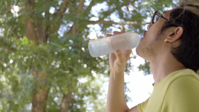 Slow motion 4K of asian sportsman drinks water from bottle .