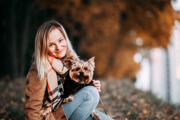Cute young girl with yorkshire terrier dog in the park in autumn