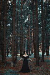 Stylish and fashionable brunette model girl in the image of Maleficent posing among mystic forest - fairytale story, cosplay