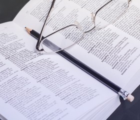 open book with glasses and pencil