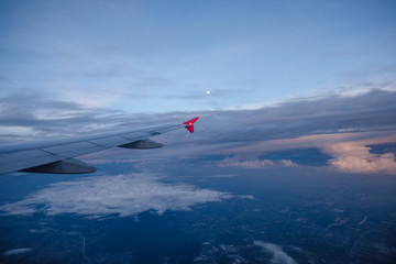 Fototapeta na wymiar Wing of an airplane after sunset with the moon on the sky