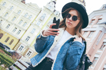 A beautiful European girl makes a selfie on the background of the city