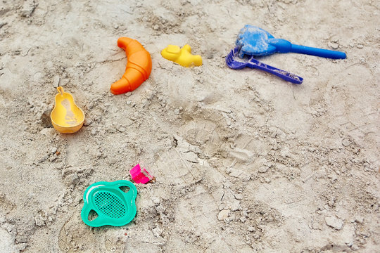 many colored plastic children's toys forgotten in the sandbox