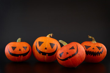 Pumpkins with painted faces on black background. Halloween backdrop.