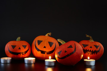 Pumpkins with painted faces on black background. Halloween backdrop.