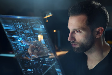 Portrait of a young man (boy) while he is using a futuristic computer with holograms.  Concept:...