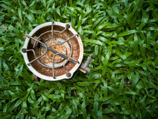 Old rust oil burner Was left on a green lawn.