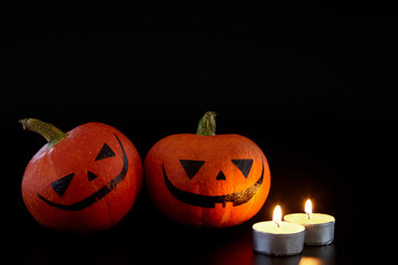 Pumpkins with painted faces on black background. Halloween backdrop.