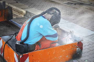 Welders in special suits and oxygen masks perform welding work on the tram tracks.