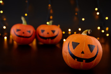 Pumpkins with painted faces on black background. Halloween backdrop.