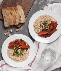 Red hot curry dish with vegetables  and bread, served in a white plate. Top view