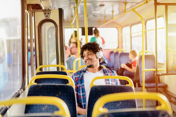 Young modern Afro-American man sitting alone in a public transport and listening to the music....