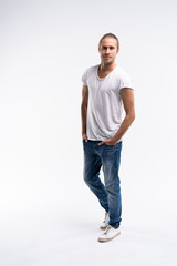 Fototapeta premium Full length of a cute young man in jeans and t-shirt looking at the camera, against white background.