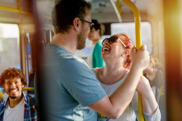 Cute middle aged couple standing in a bus. Laughing and looking at each other. Holding for a bar. © Dusan Petkovic