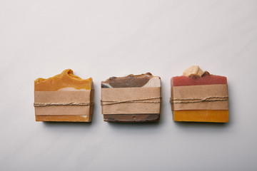 top view of row of various aromatic soap pieces on white marble surface