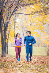 Fototapeta premium Man and woman running as fitness sport in an autumn park with colorful foliage