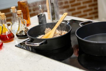 Meat frayed on fraying pan on modern stove.