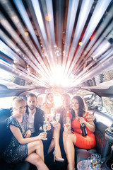Celebration in a limo, woman and men drinking champagne and having a party - obrazy, fototapety, plakaty