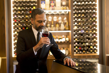 Handsome mature man tasting red wine