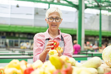 Senior woman sells vegetable on market