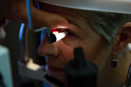 Optometrist examining patient eyes with eye test equipment in