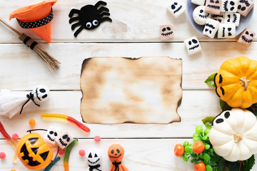 Top view of old paper with yellow ghost pumpkins on wooden board. halloween concept.