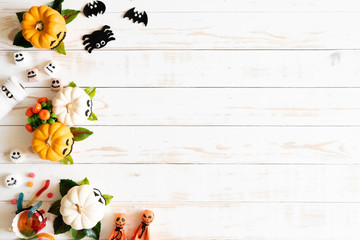 Top view of white and yellow ghost pumpkins with bat spider mummy jelly worm and gift box on white wooden background. halloween concept.