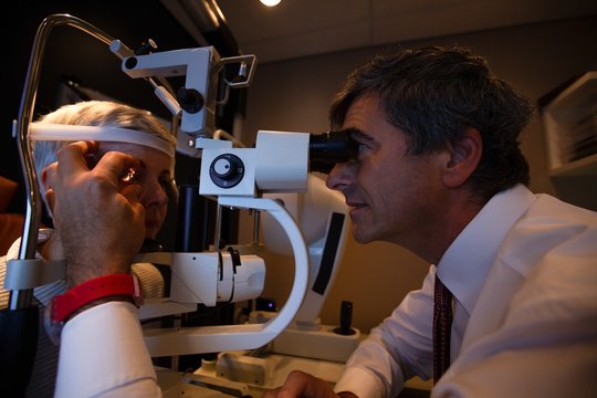 Optometrist examining patient eyes with slit lamp