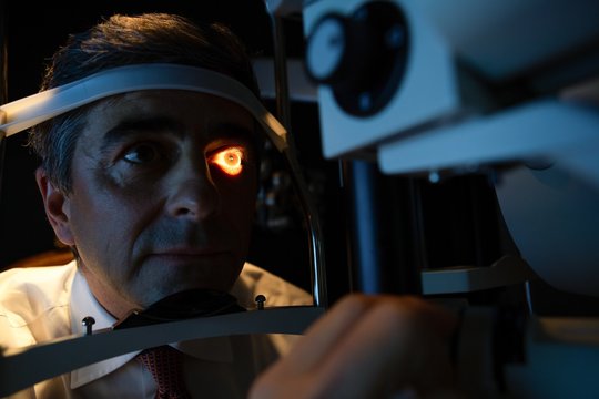 Optometrist examining patient eyes with slit lamp