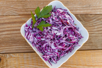 Red cabbage salad with onion and mayonnaise on wooden table. Top view