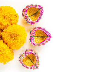 Happy Diwali - Clay Diya lamps lit during Dipavali, Hindu festival of lights celebration. Colorful traditional oil lamp diya with yellow flower on white background