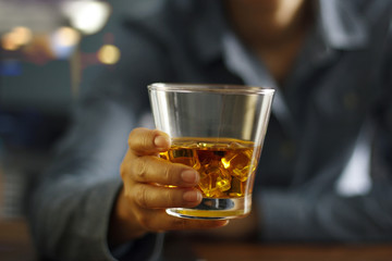 Close-up men holding whiskey drink alcoholic beverage at bar counter in the pub background