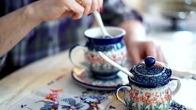 Female hand mixing sugar in cup of tea focus on hands
