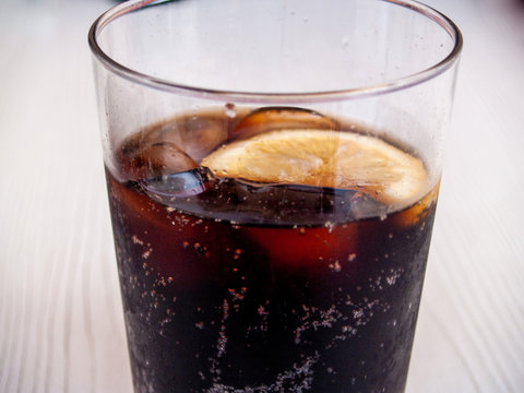 A glass of coke with a slice of lemon