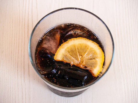 A glass of coke with a slice of lemon