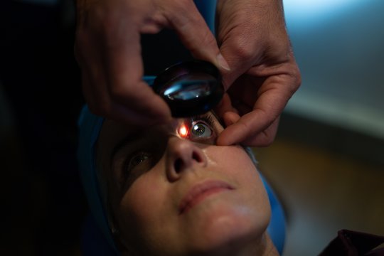 Optometrist examining patient eyes with eye test equipment in