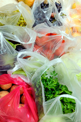 Various fruits and vegetables in plastic bags are on the floor in the house. Bought on the market