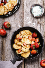 Cheese Buttermilk Pancakes or fritters with strawberry on pan with apples and coconut cranch on vintage wooden table