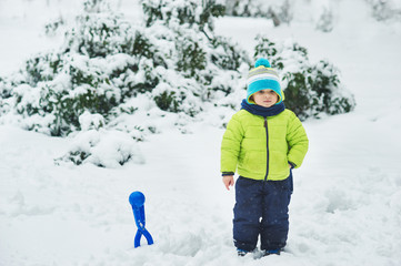 Fototapeta na wymiar the boy in snow in the Park. A boy plays in winter Park. Adorable child walking in snow winter forest