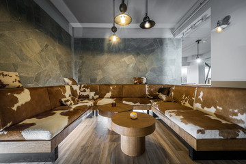 Spacious interior of restaurant with luxury cowhide sofa - obrazy, fototapety, plakaty