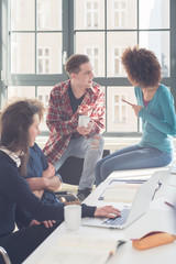 Cheerful students having a funny loud conversation  during break in the classroom of a modern...